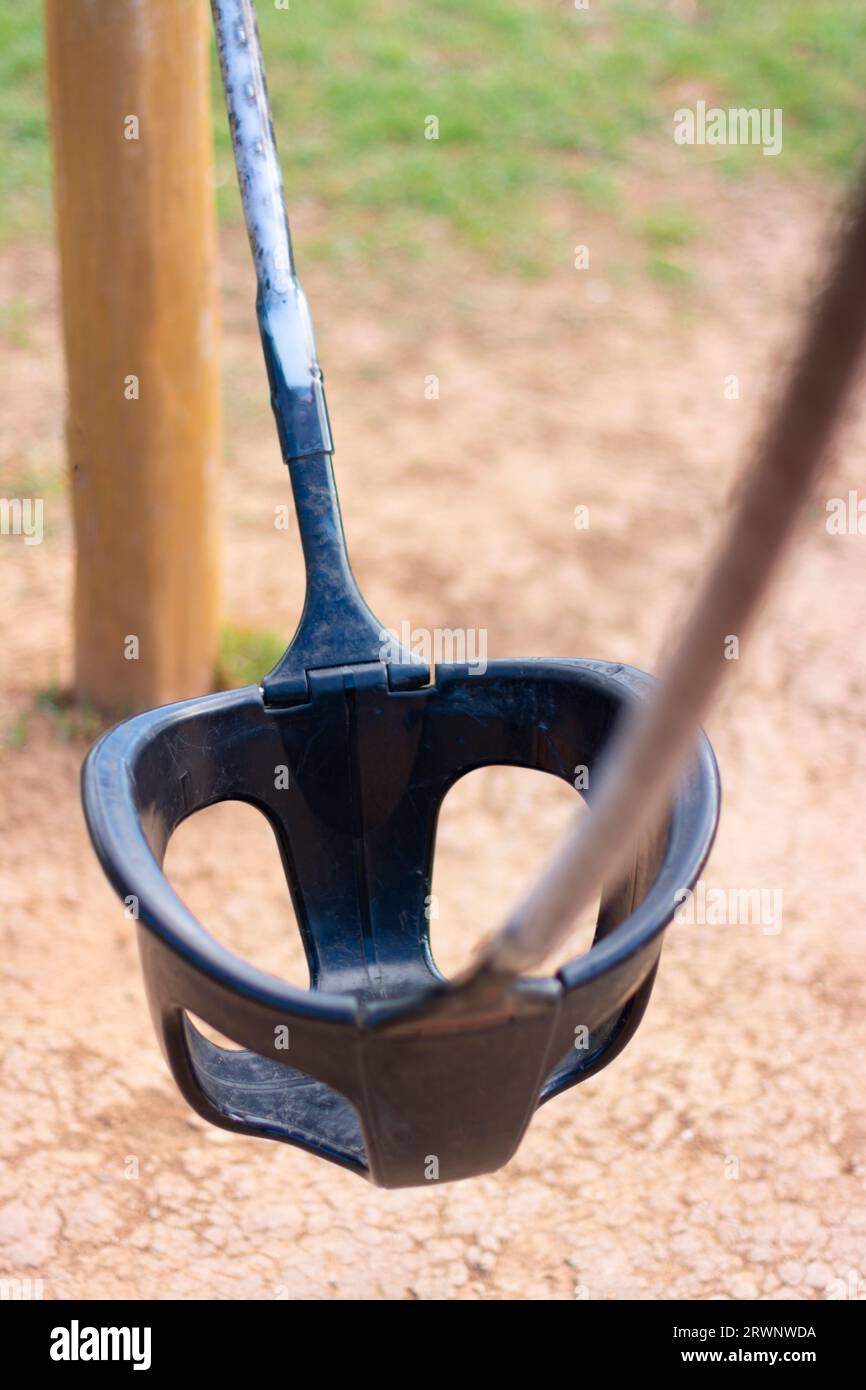 Foto dall'alto di un'altalena moderna in materiale plastico, in un parco giochi, solitario, con sfocatura su una linea sospesa. Concetto di solitudine, aband Foto Stock