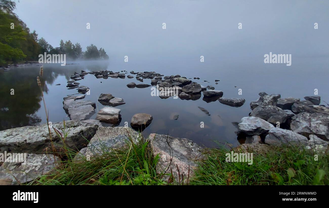 Quando la nebbia mattutina cerca di sollevarsi dal lago, e far uscire il sole. Foto Stock