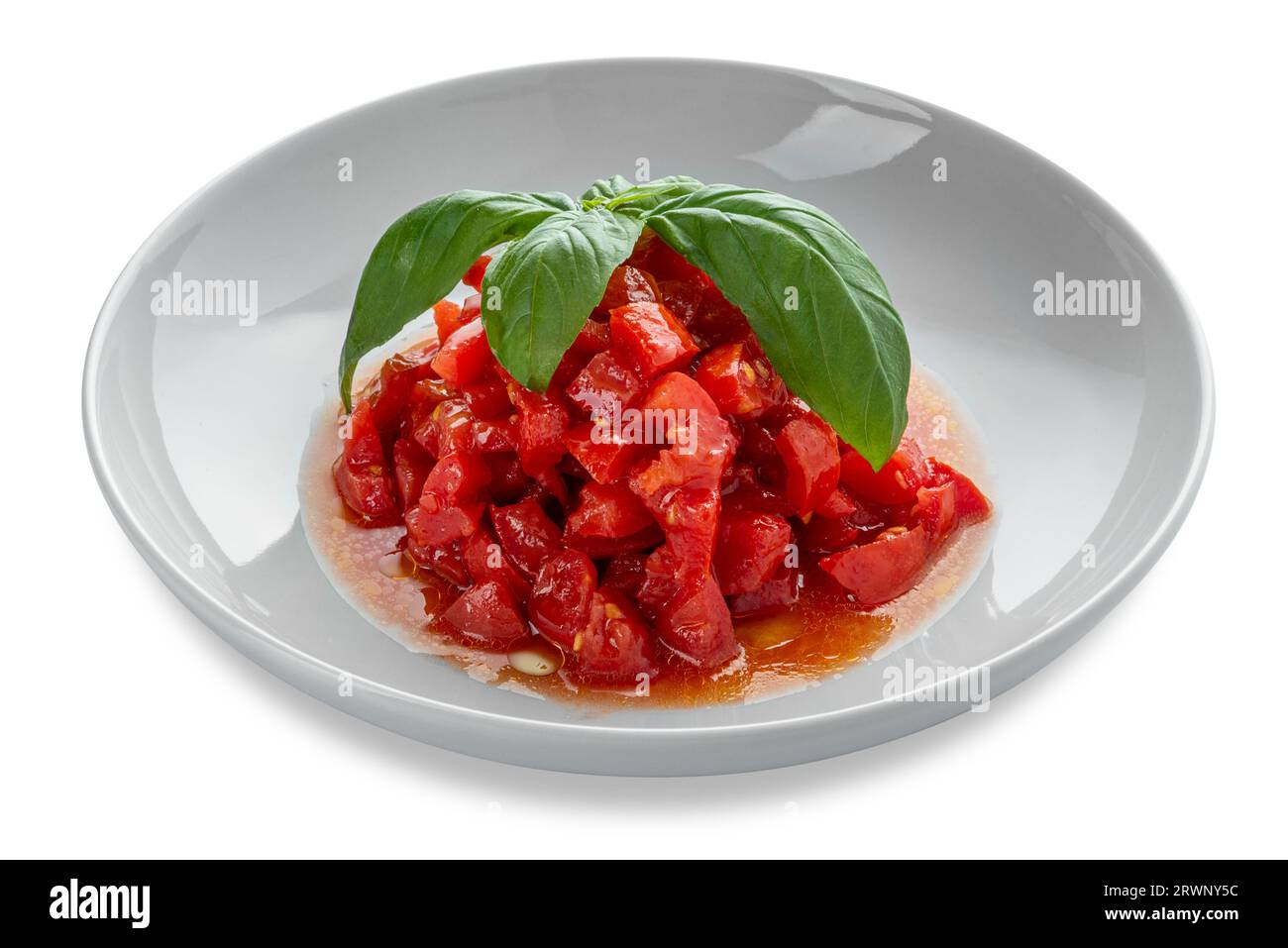 Insalata di pomodori crudi tritati e tagliati a dadini conditi con olio d'oliva e con foglie di basilico in piatto bianco isolato su sentiero di clippingh bianco incluso Foto Stock