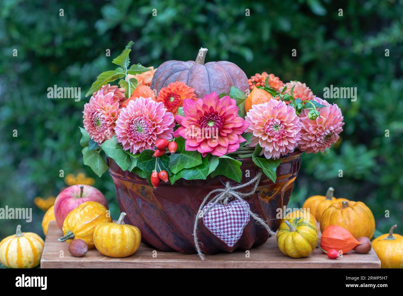 composizione floreale con dahlias arancio e zucca in un vecchio stampo di guglhupf Foto Stock