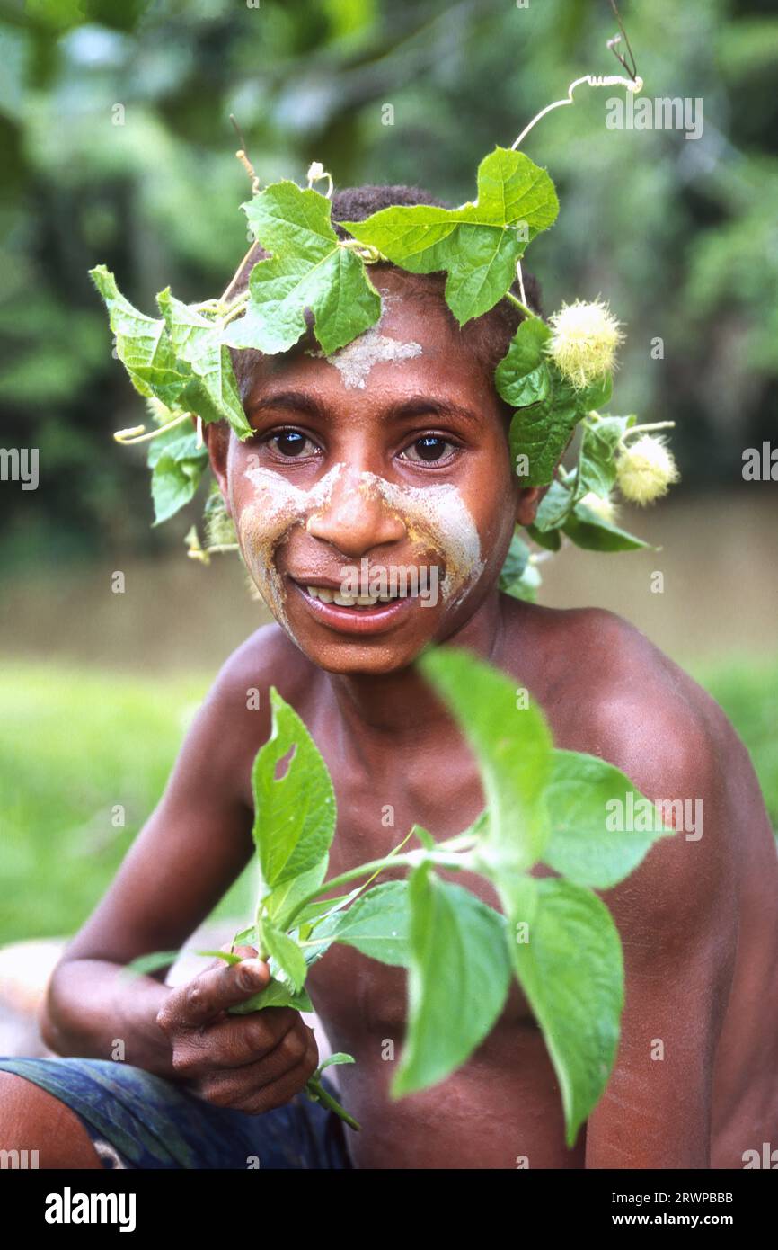 Giovane ragazzo tribale con foglie intorno alla testa, Papua nuova Guinea Foto Stock