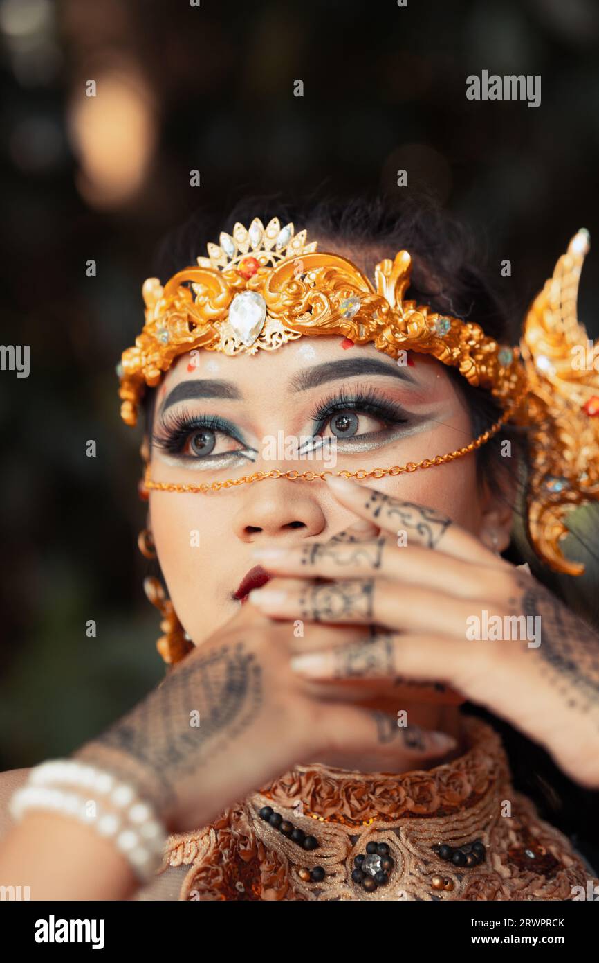 Bella sposa indiana che indossa una corona dorata e una collana dorata con tatuaggi sulle mani prima della cerimonia nuziale Foto Stock