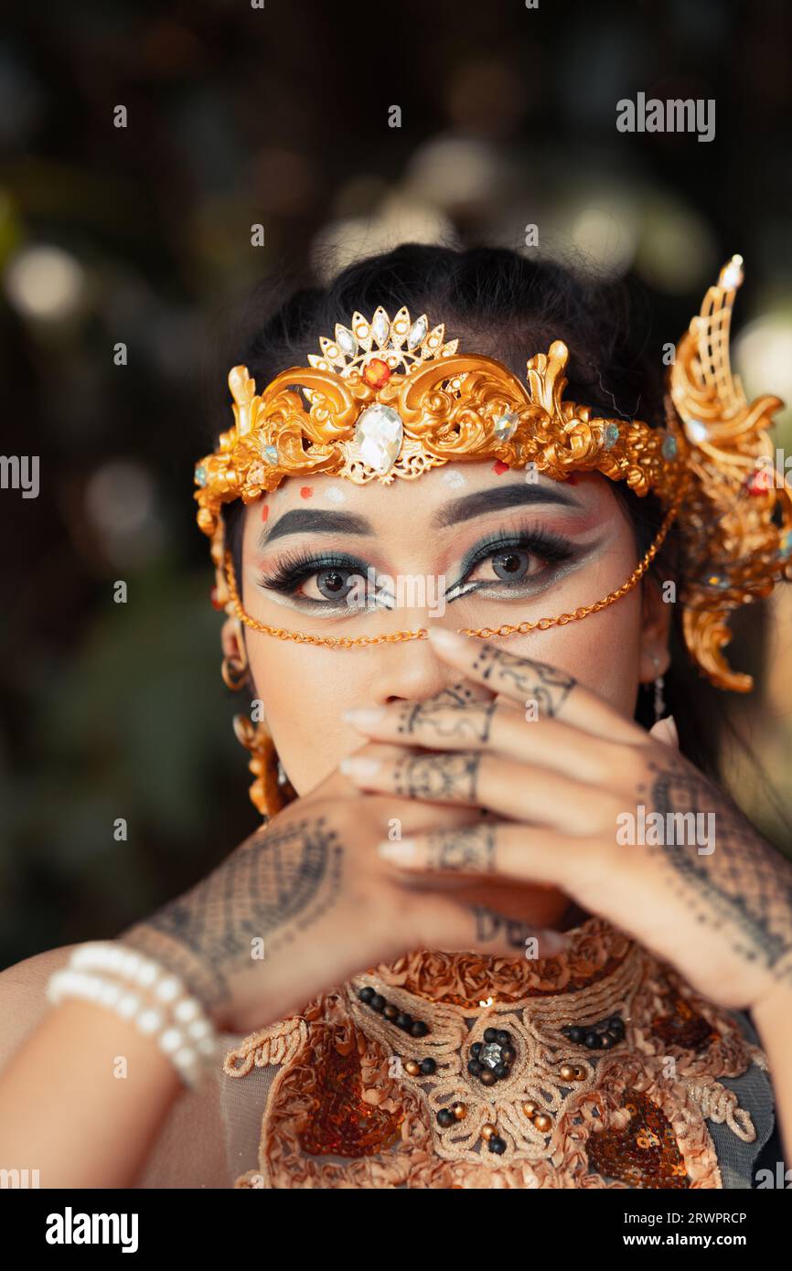Bella sposa indiana che indossa una corona dorata e una collana dorata con tatuaggi sulle mani prima della cerimonia nuziale Foto Stock