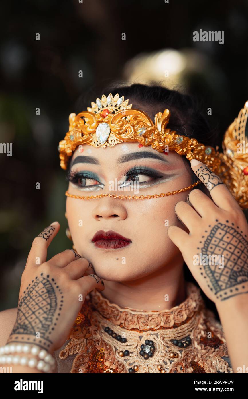 Bella sposa indiana che indossa una corona dorata e una collana dorata con tatuaggi sulle mani prima della cerimonia nuziale Foto Stock