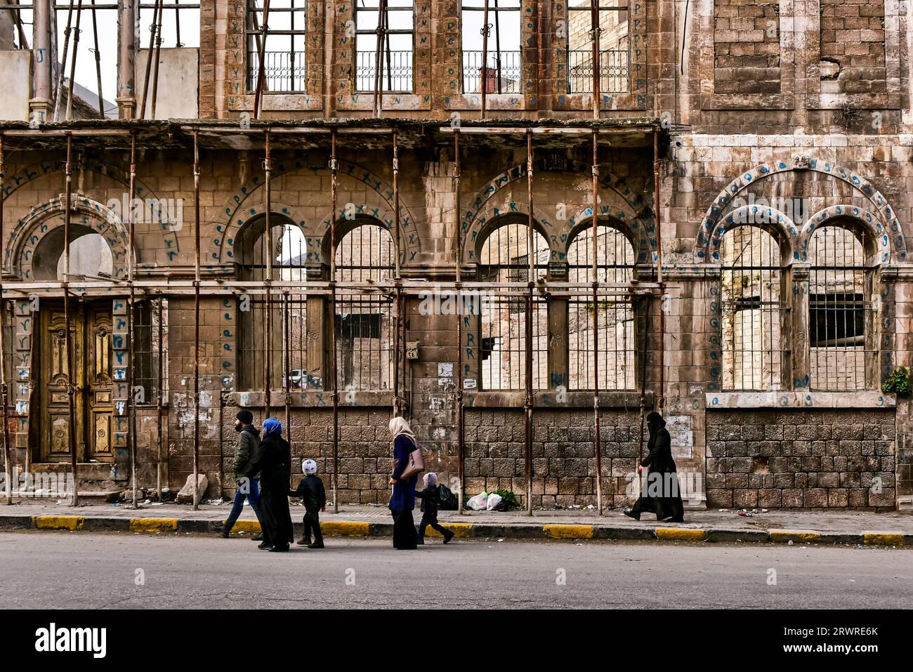 Civili locali che camminano tra le rovine di un edificio (alcune mura) nel centro della vecchia Hama, in Siria Foto Stock