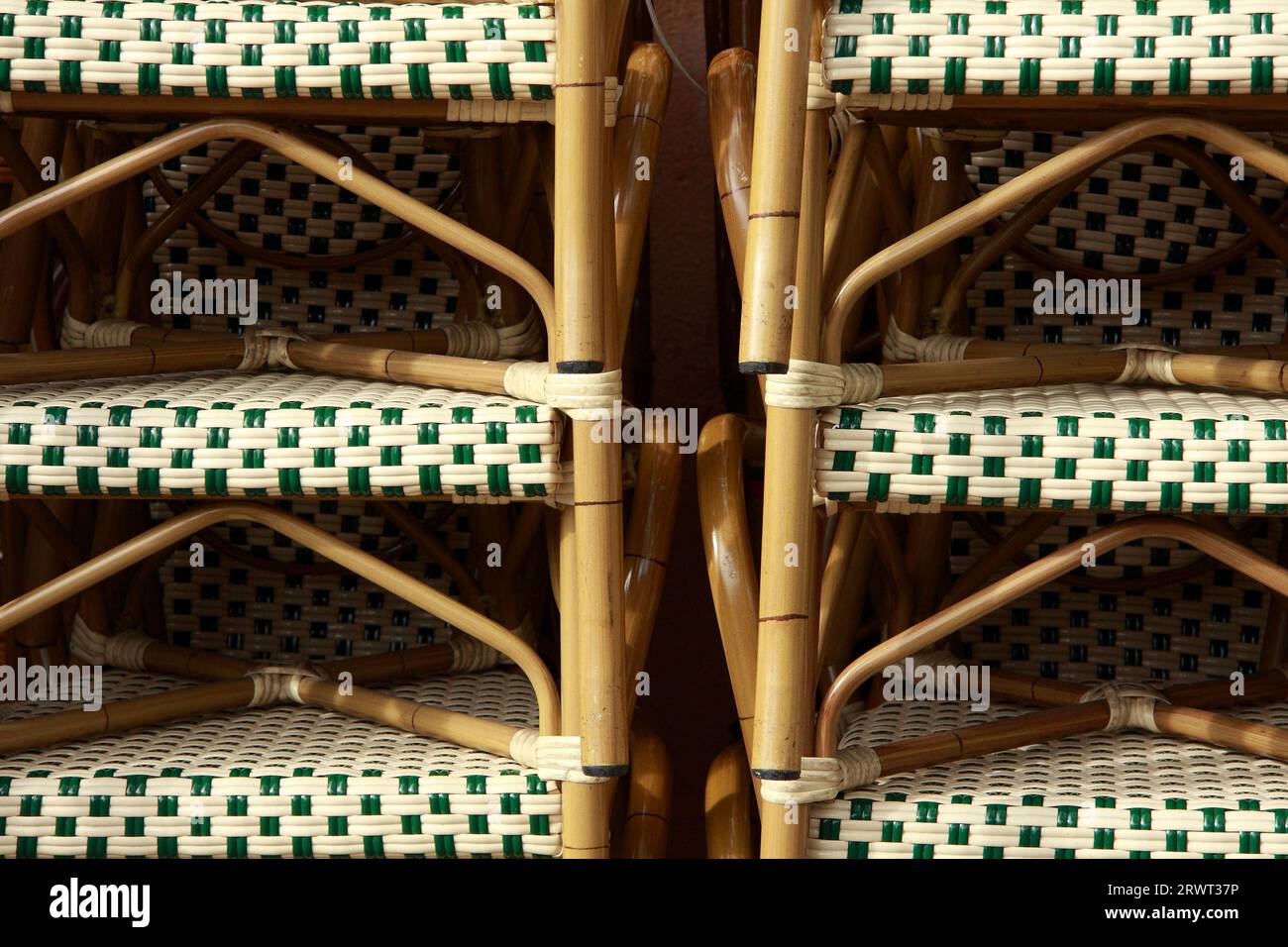 Due file di sedie in vimini in rattan impilate con rivestimento in tessuto bianco-verde, ritagliato Foto Stock