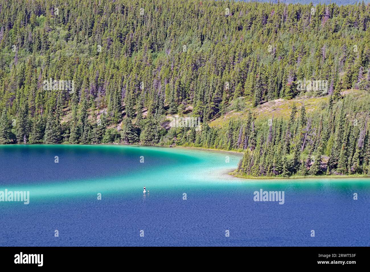 Lago trasparente e trasparente con acqua di colore verde, paddler solitario, foresta e montagne, lago Emerald, autostrada Klondike, Carcross, territorio dello Yukon, Canad Foto Stock