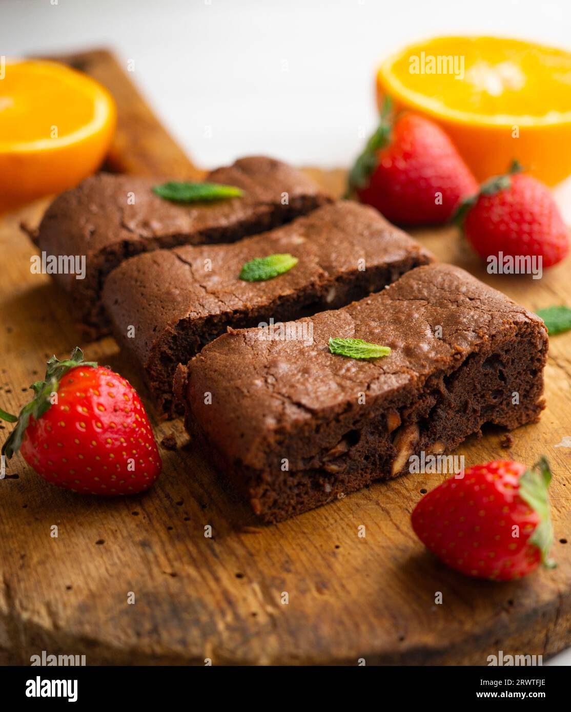 Brownie al cioccolato tagliato a porzioni e decorato con fragole e menta. Foto Stock