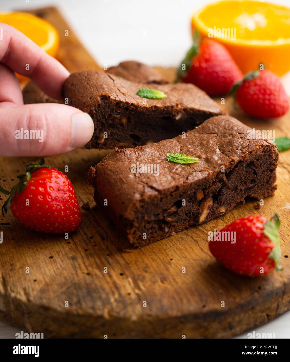Brownie al cioccolato tagliato a porzioni e decorato con fragole e menta. Foto Stock