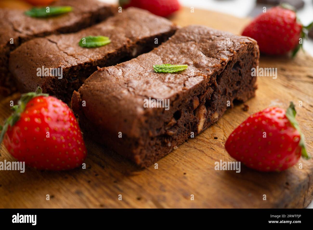Brownie al cioccolato tagliato a porzioni e decorato con fragole e menta. Foto Stock