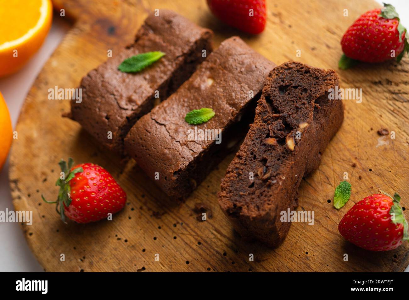 Brownie al cioccolato tagliato a porzioni e decorato con fragole e menta. Foto Stock