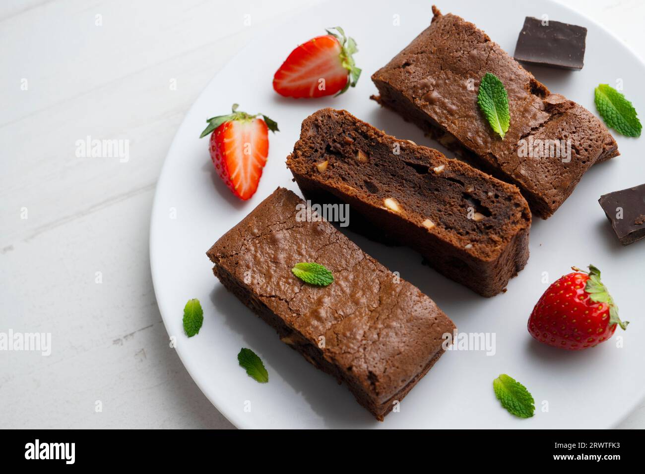 Brownie al cioccolato tagliato a porzioni e decorato con fragole e menta. Foto Stock