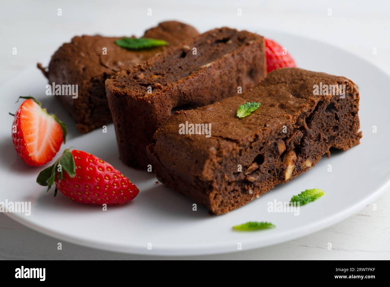 Brownie al cioccolato tagliato a porzioni e decorato con fragole e menta. Foto Stock