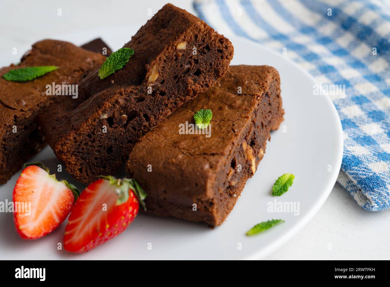 Brownie al cioccolato tagliato a porzioni e decorato con fragole e menta. Foto Stock