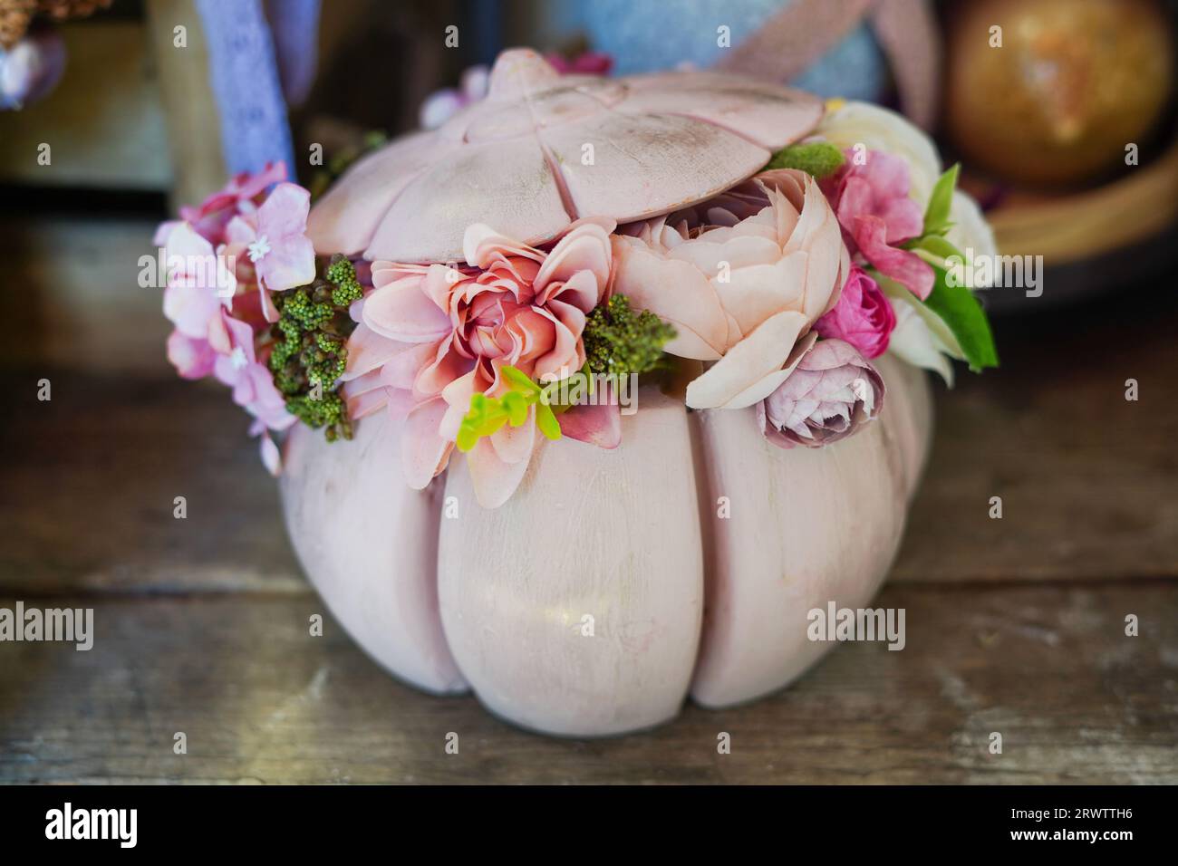 Bellissima composizione di fiori nella zucca rosa su un tavolo di legno Foto Stock