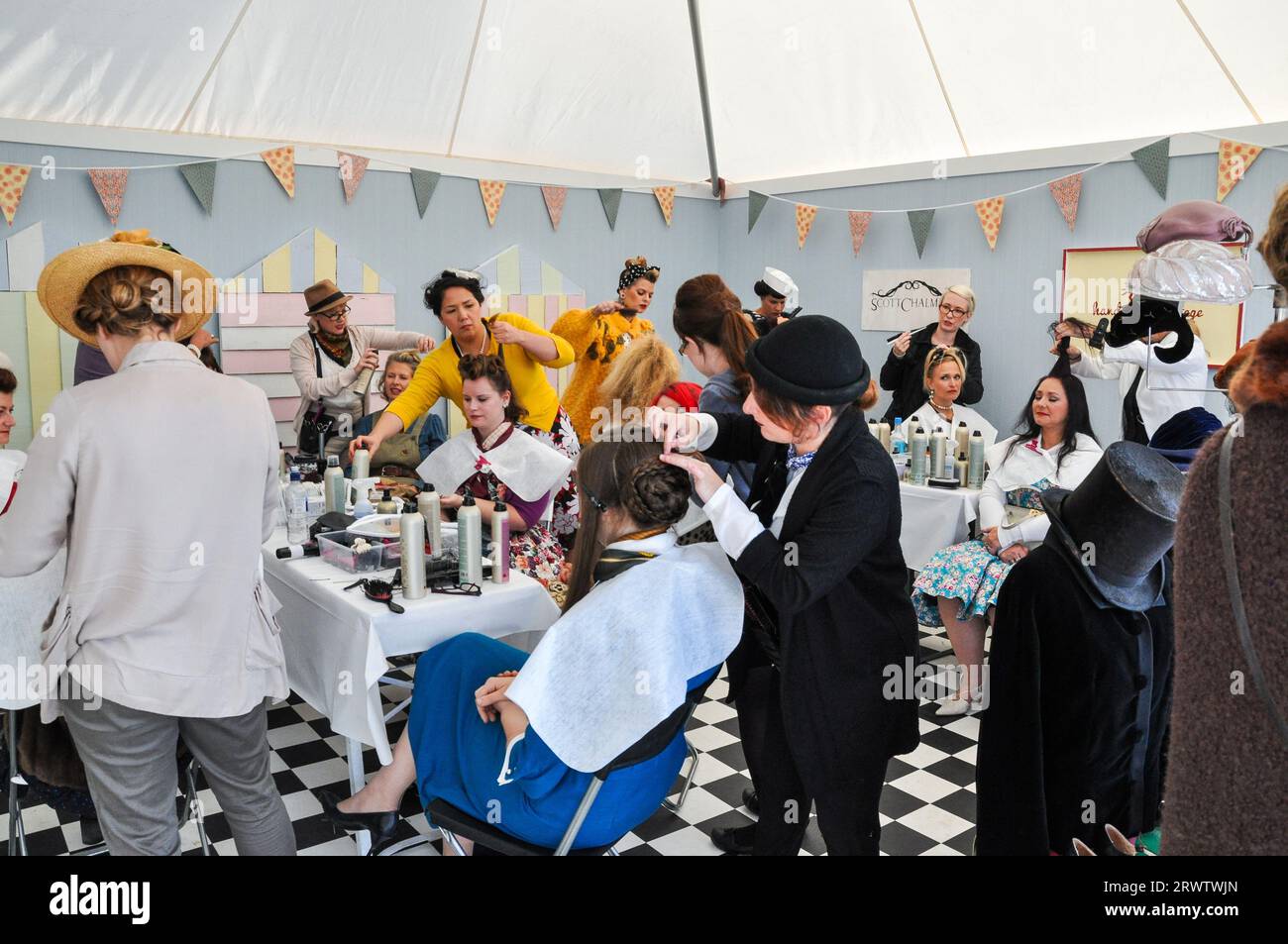 Le femmine in un salone di bellezza e parrucchiere offrono un tocco di stile retrò al pubblico al Goodwood Revival, Regno Unito. Styling dei capelli delle donne in corso Foto Stock