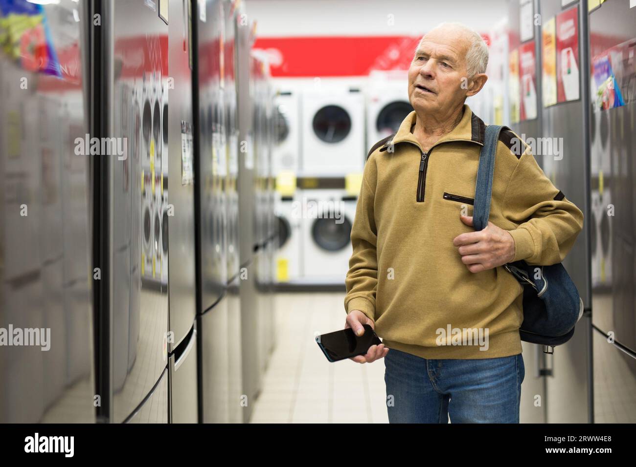 Pensionato Senor MAN che acquista un frigorifero nello showroom del negozio di elettrodomestici Foto Stock