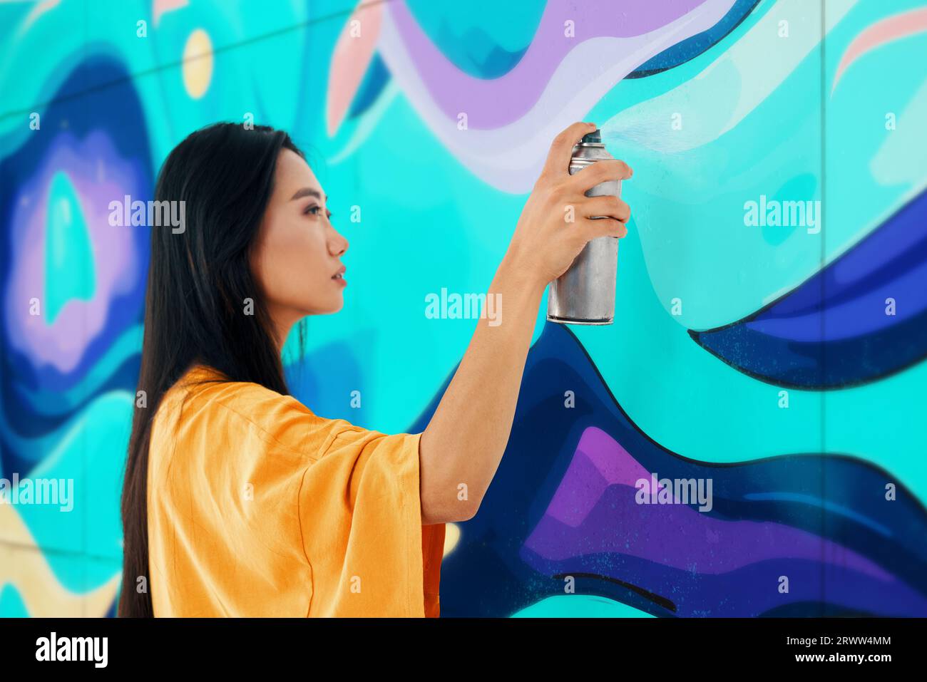 Artista di strada femminile che dipinge graffiti colorati sul muro arte moderna, concetto urbano. Foto Stock