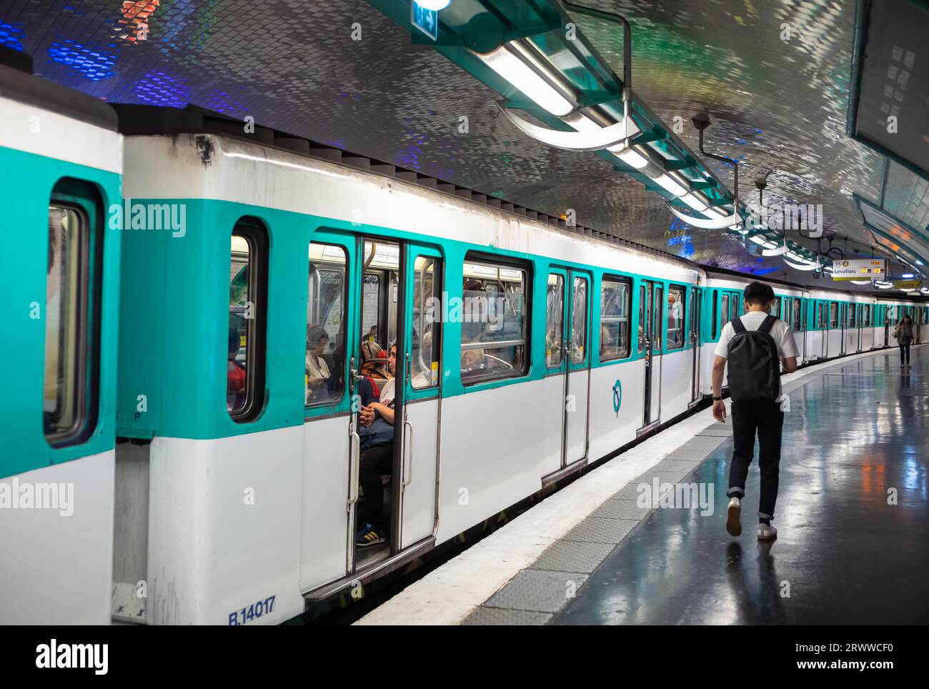 Un uomo cammina sul binario mentre un treno della metropolitana di Parigi si prepara ad uscire dalla stazione Gambetta sulla linea 4 a Parigi, Francia. Foto Stock
