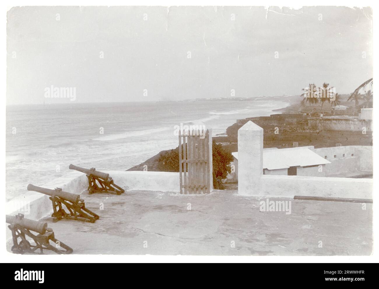 Ammira la spiaggia dai bastioni del castello di Osu, allora conosciuto come Fort Christiansborg, vicino ad Accra. In primo piano c'è una fila di cannoni che si affacciano sul mare. Didascalia del manoscritto originale: 5 km a ovest di Accra. Foto Stock