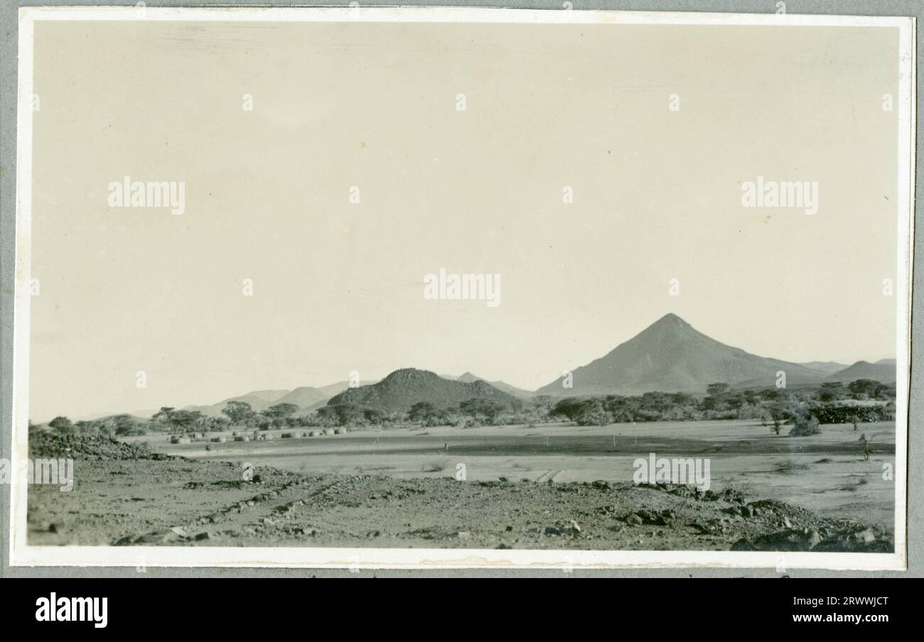 Una delle sette immagini intitolate "North Kavirondo Agricultural Show". Mumias. Gen: 1931. » Un gruppo di persone africane vestite con un mix di abiti in stile occidentale e costumi tradizionali attendono la presentazione al Governatore. Foto Stock