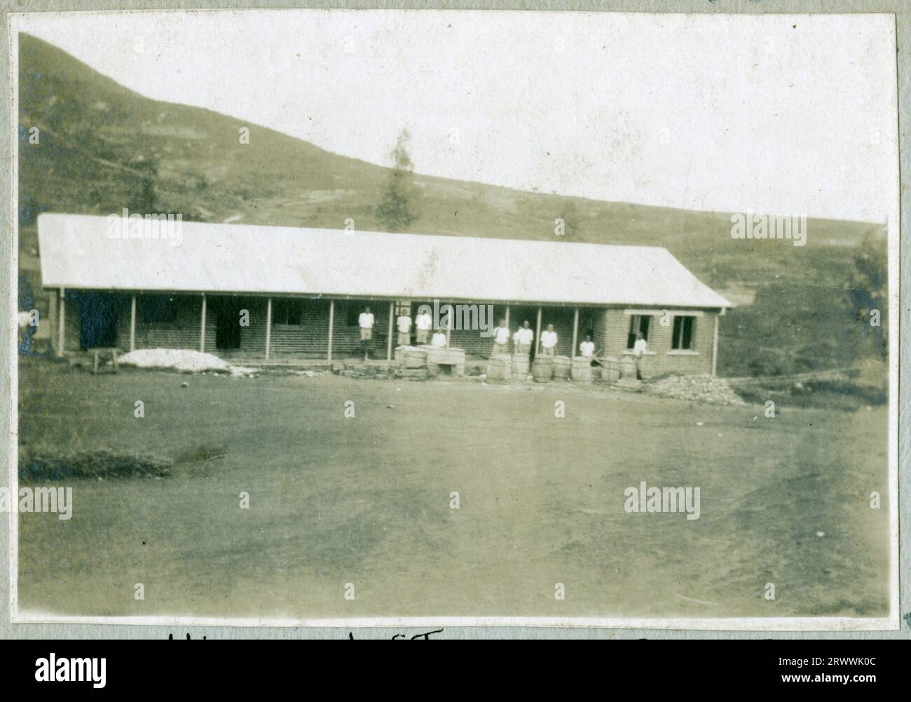 Vista di un edificio in mattoni con veranda e ringhiere bianche. Un uomo europeo in uniforme e che indossa un elmetto Pith sta fuori. Didascalia del testo originale: Stazione di polizia di Machakos. Foto Stock