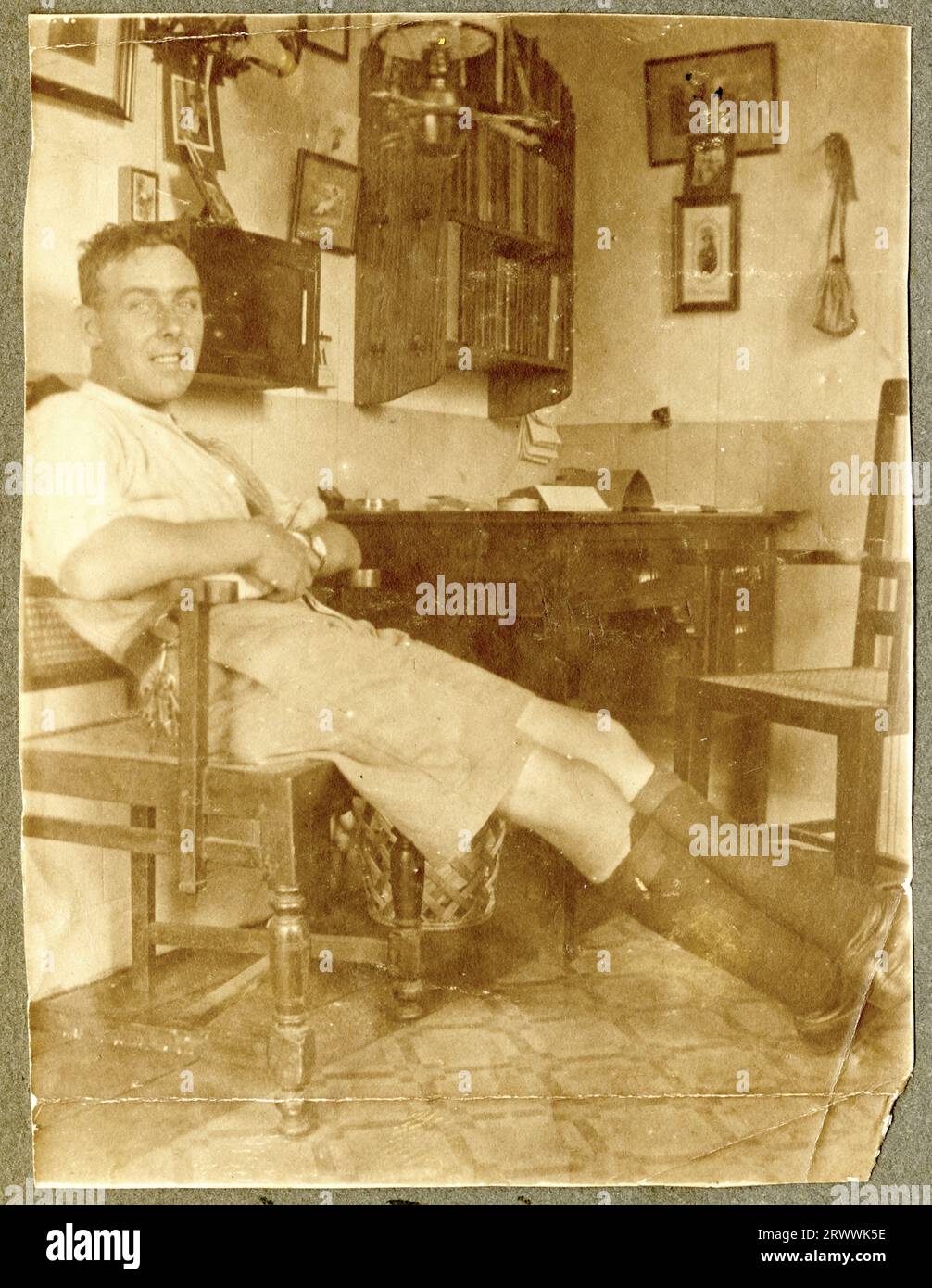 Foto di un giovane Charles Bungey che si rilassa su una sedia accanto a una scrivania in quello che sembra un ufficio domestico. Didascalia del testo originale: "The Den". 1912. Foto Stock