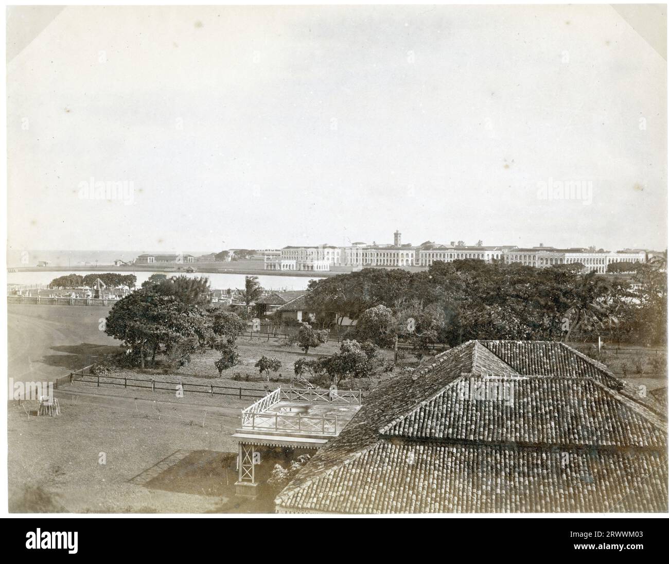 Vista da lontano della caserma, un lungo edificio bianco a più archi . C'è un cimitero in primo piano. La didascalia recita: The Barracks, Colombo. Foto Stock