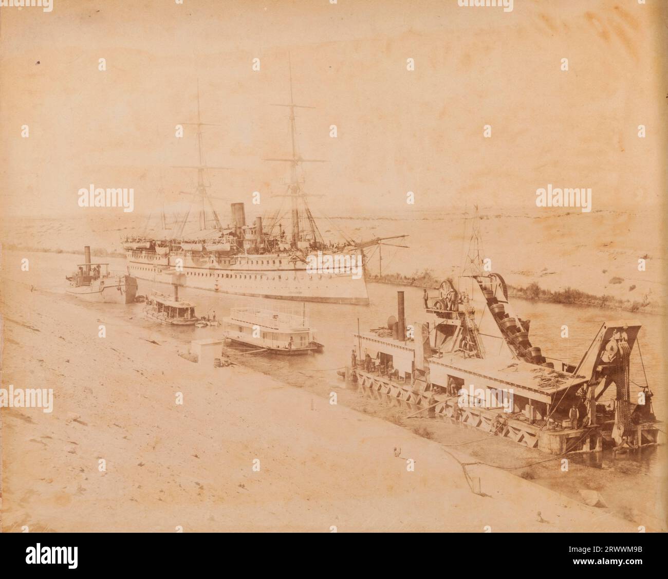 Vista di una nave da trasporto truppe con tre alberi lungo il canale di Suez. Ci sono piccole barche fluviali e una nave cargo ormeggiata sul lato del canale. Fotografia scattata dai fratelli Zangaki. Didascalia in negativo: Zangaki. Malabar [illeggibile]. La didascalia scritta a mano recita: 1893 Her Majestys Troopship Malabar nel Canale di Suez. Foto Stock