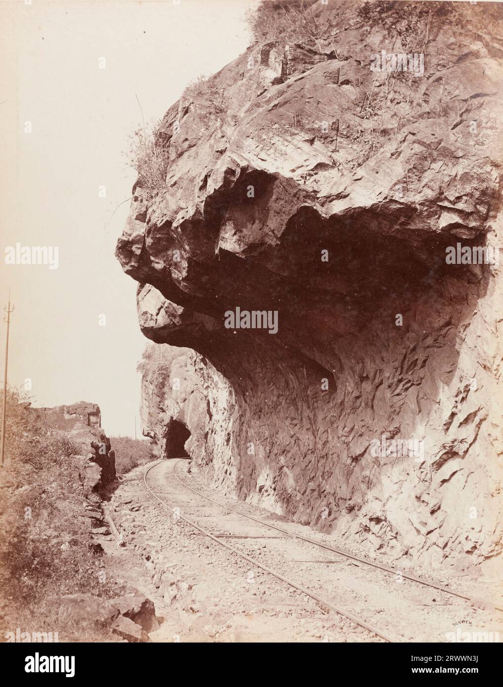 Una sezione della ferrovia passa attraverso un tunnel in una roccia. C'è una grande formazione rocciosa a strapiombo e un po' di fogliame a sinistra. La didascalia recita: Capo dei leoni Colombo Kandy Ry. Scritto in negativo: Scowen. Scowen & Co. Era uno studio fotografico di successo che lavorava a Ceylon alla fine del XIX secolo. Foto Stock