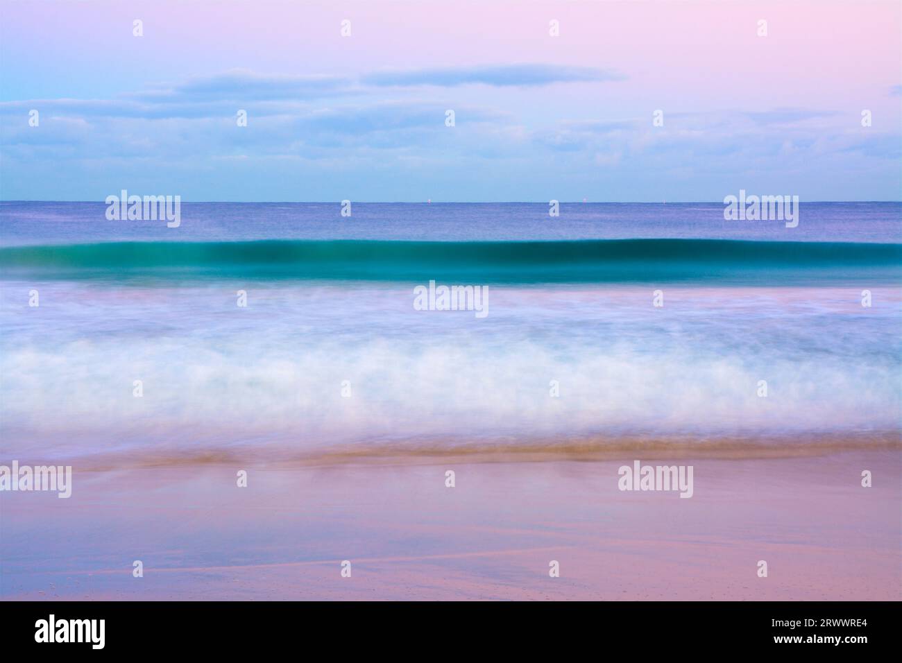 Onde che si infrangono all'alba con sfumature rosa a Leighton Beach a North Fremantle, Perth, Australia Occidentale Foto Stock