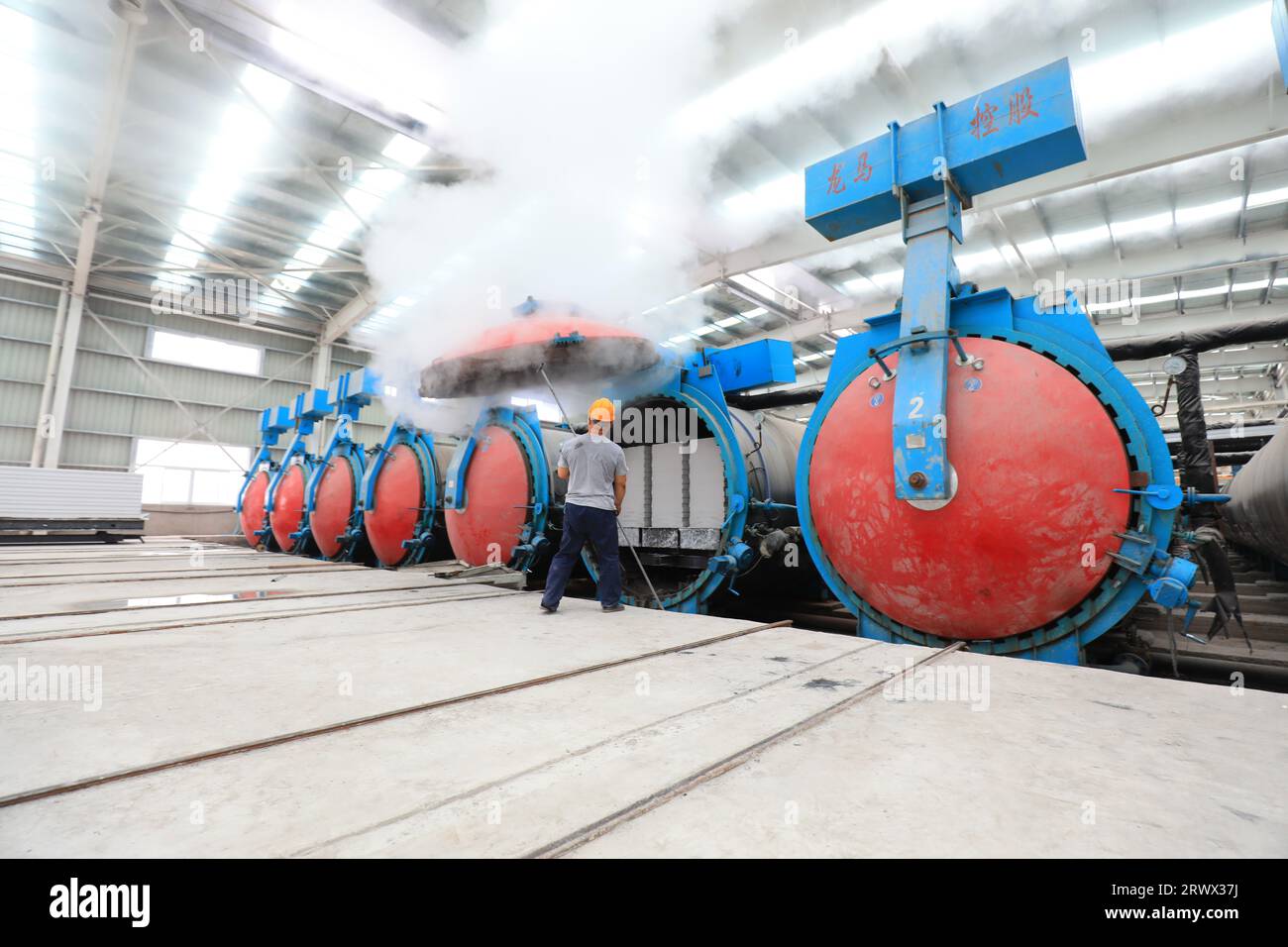 Contea di Luannan, Cina - 27 giugno 2023: I lavoratori stanno aprendo l'autoclave sulla linea di produzione di pannelli divisori leggeri in fabbrica Foto Stock