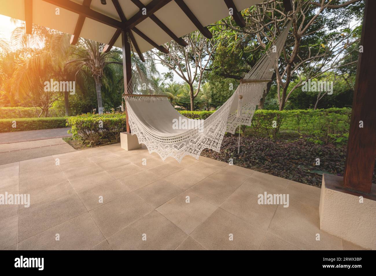 Amaca vuota sotto il tetto ombreggiato nelle soleggiate giornate tropicali Foto Stock