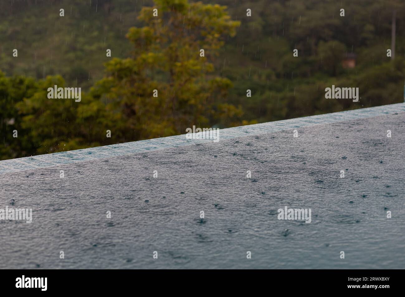 L'acqua piovana colpisce il terreno quando la luce è buia Foto Stock