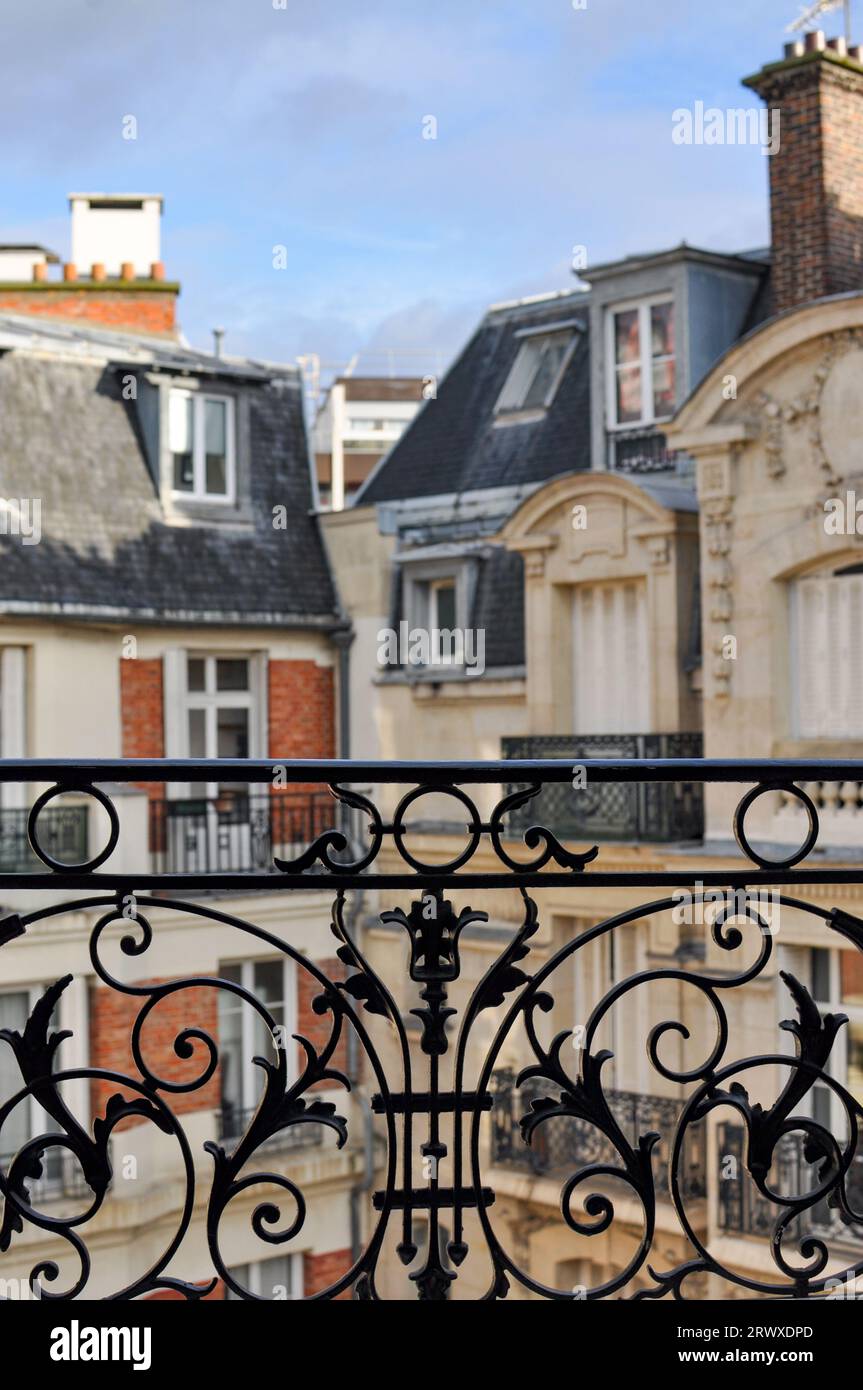 Tipici edifici parigini di stile architettonico Haussmanniano visti attraverso un balcone in ferro battuto nero Foto Stock