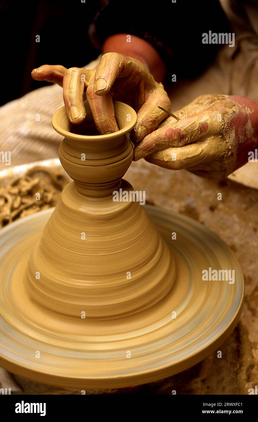 Primo piano di Potter che forma l'argilla su una ruota rotante Foto Stock