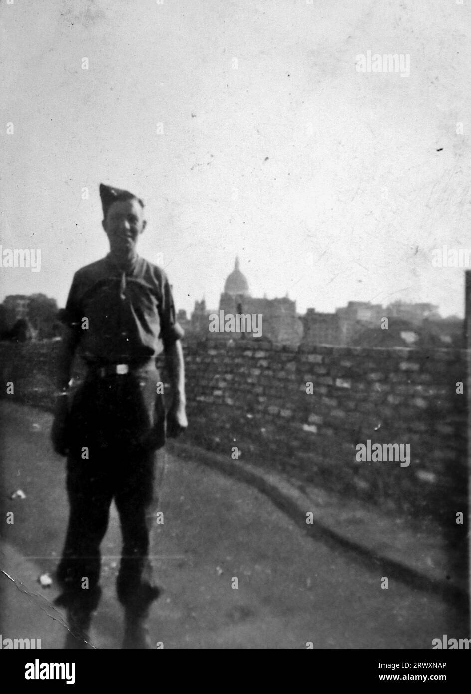 Un soldato britannico isolato accanto a un muro di mattoni, Chiswell Street, Londra, al ritorno a casa. Fotografia rara: Da una collezione compilata da un militare britannico sconosciuto che copre la No. 1 Composite Demonstration, AA Battery, tour degli Stati Uniti, dall'11 luglio 1943. Si tratta di una delle oltre cento immagini della collezione che erano in media di circa 4 x 3 pollici. Foto Stock