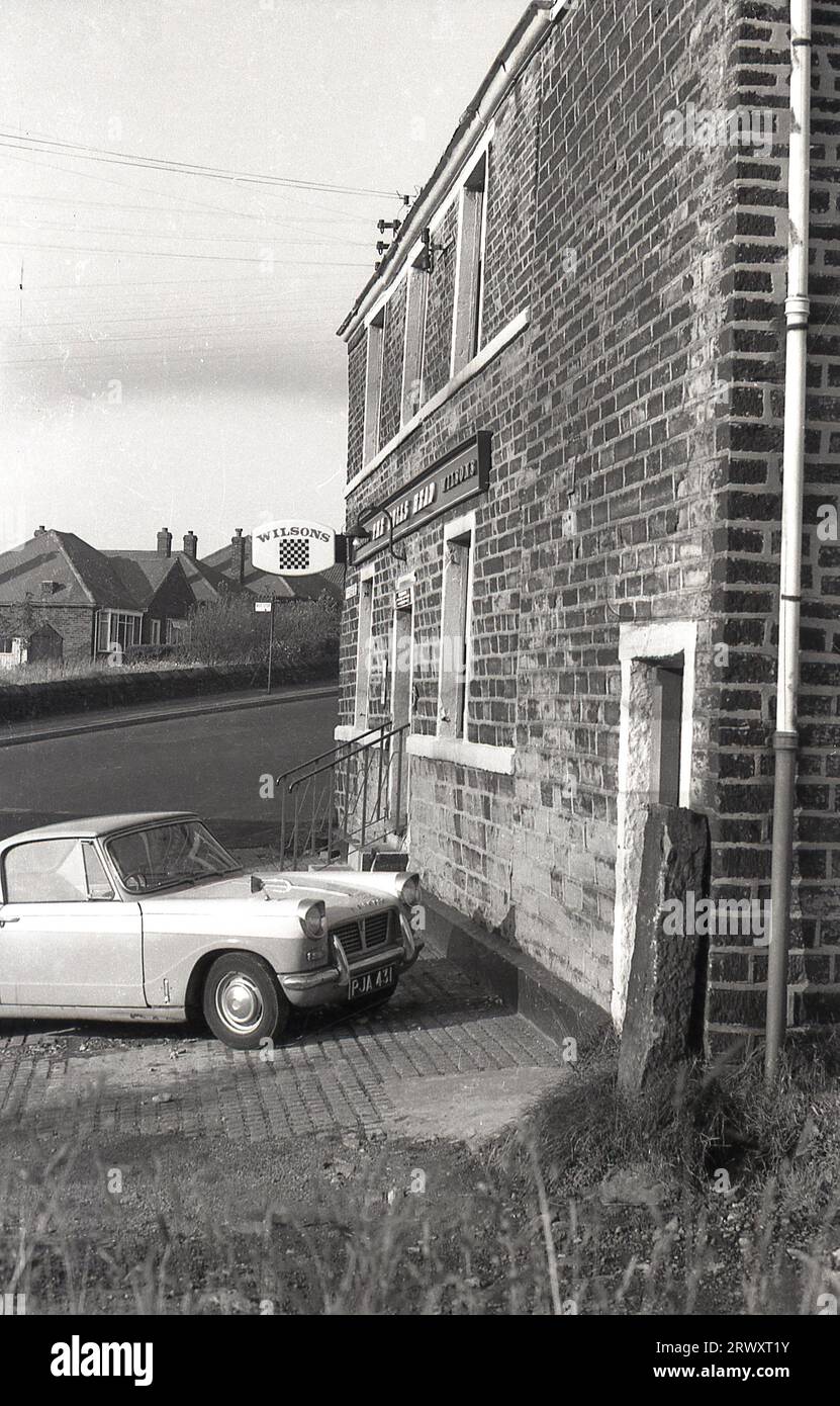 Anni '1960, storico, un Triumph Herald parcheggiato fuori da una casa pubblica di Wilsons, The Bulls Head, Ripponden Rd, Oldham, Lancashire, Inghilterra, Regno Unito. Questa piccola vettura a due porte fu costruita per la prima volta dalla Standard-Triumph Company di Coventry nel 1959 e con una carrozzeria progettata da Giovanni Michelotti fu prodotta, in diverse versioni, fino al 1971. Foto Stock