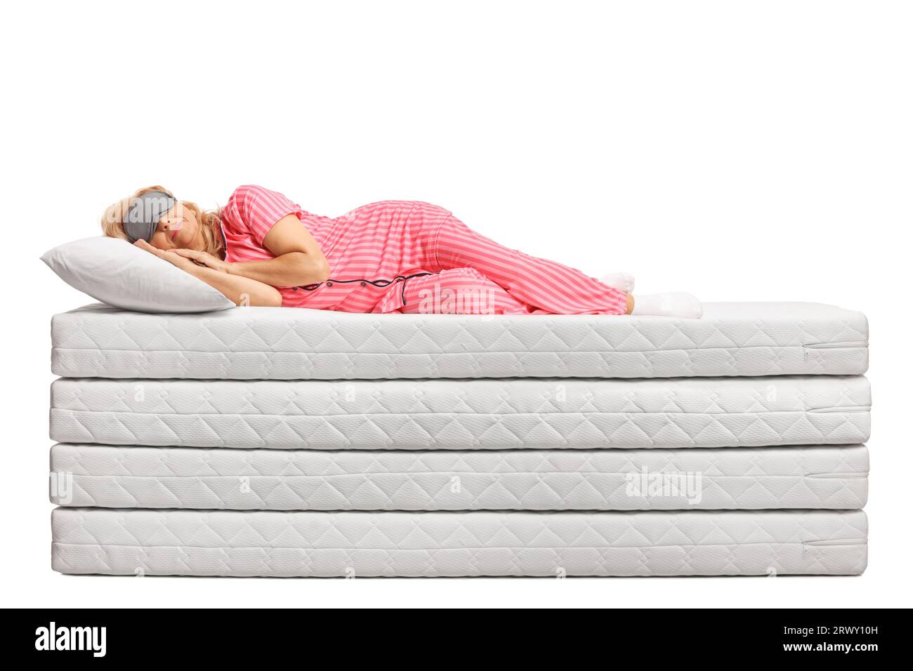 Donna in pigiama che dorme su una pila di materassi isolati su sfondo bianco Foto Stock