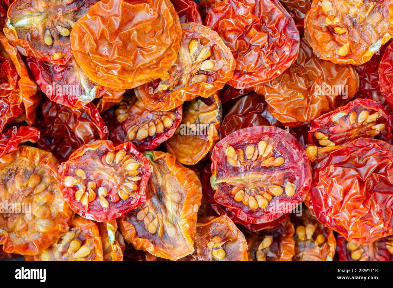 Un mucchio di pomodori ciliegini secchi rossi e arancioni Foto Stock