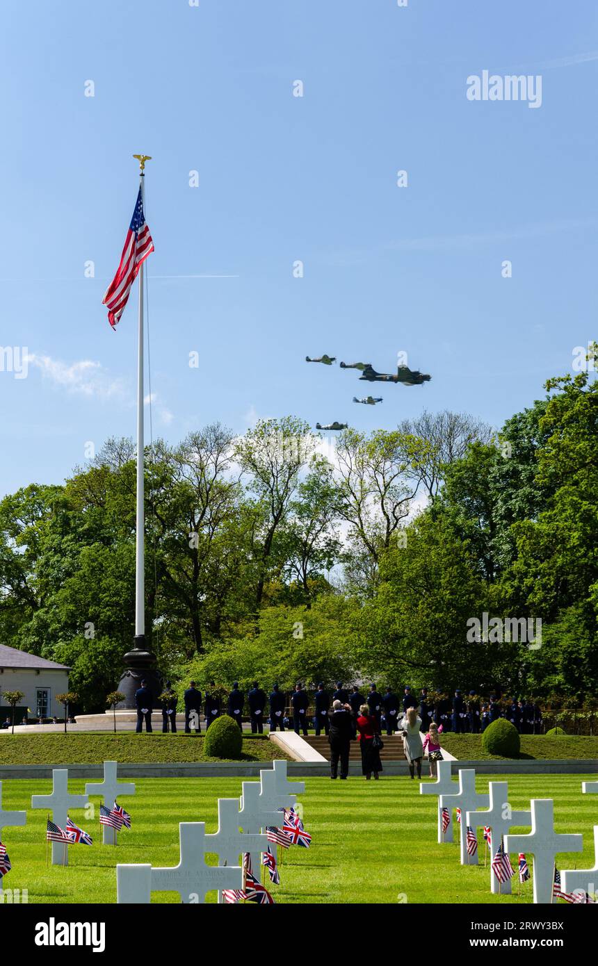 B-17 Flying Fortress Sally B e gli aerei da caccia effettuata una flypast commemorative oltre il Cambridge Cimitero e memoriale americano a bandiera statunitense, attraversa Foto Stock