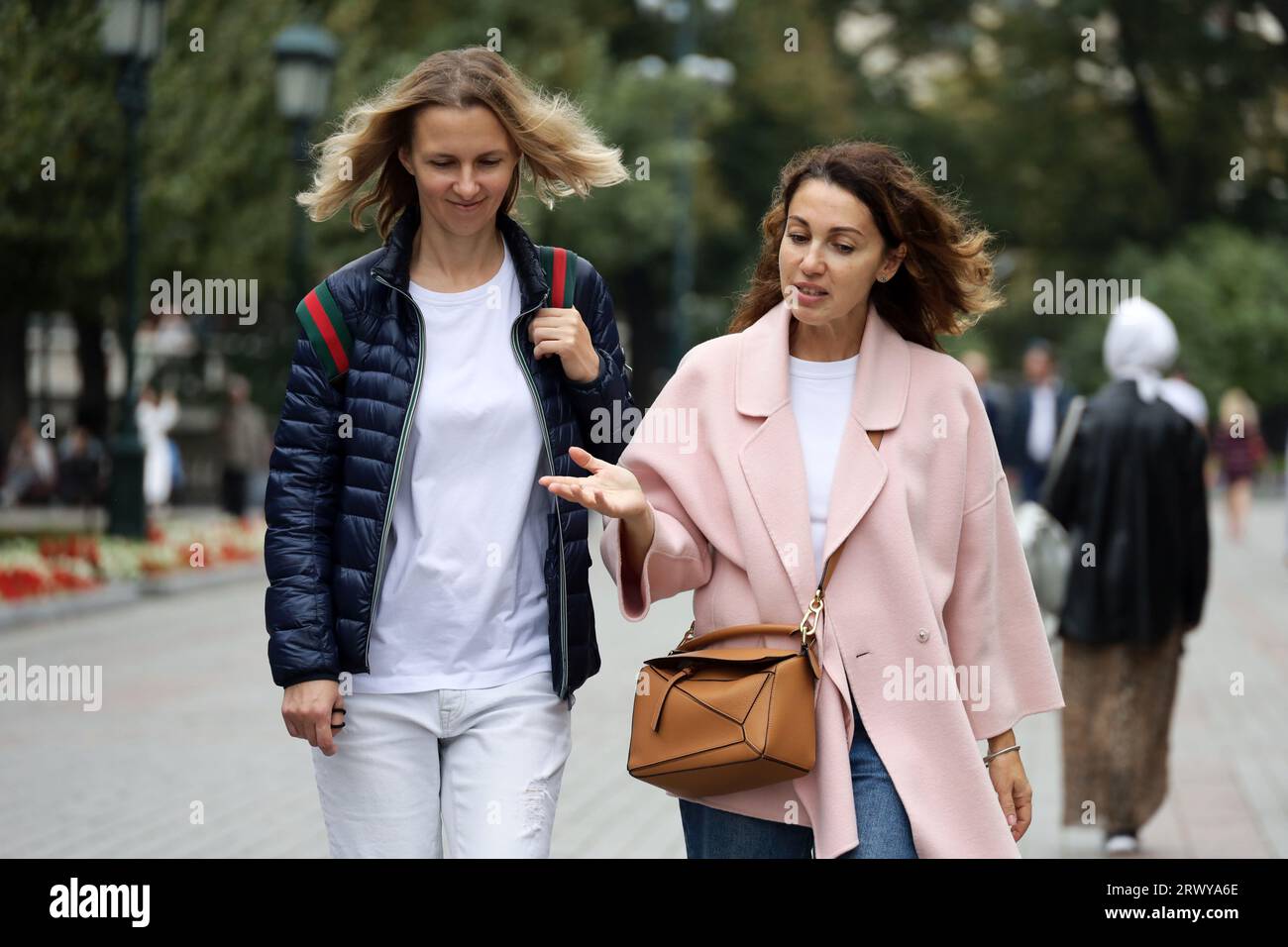 Due donne che parlano emotivamente per strada. Ragazze che camminano nella città autunnale Foto Stock