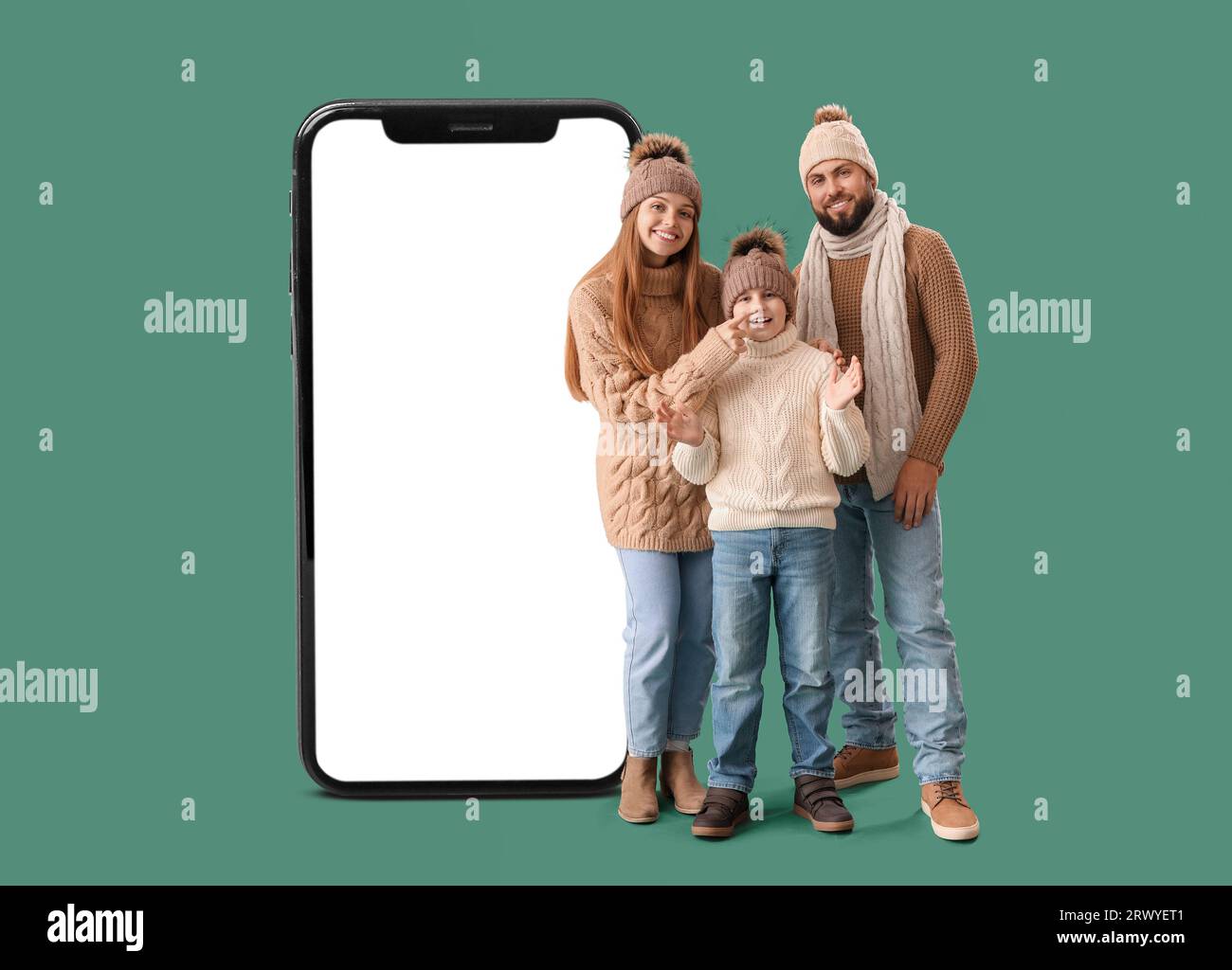 Famiglia felice in abiti caldi e grande smartphone su sfondo verde Foto Stock