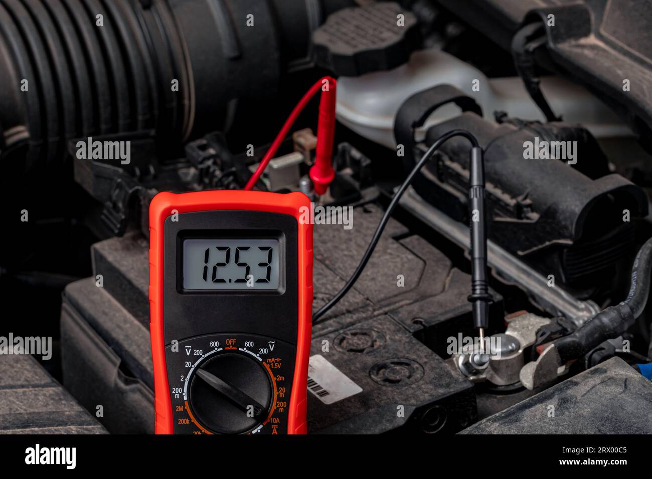 Tester per batterie che controlla la tensione della batteria dell'auto. Concetto di manutenzione, riparazione e assistenza del veicolo. Foto Stock
