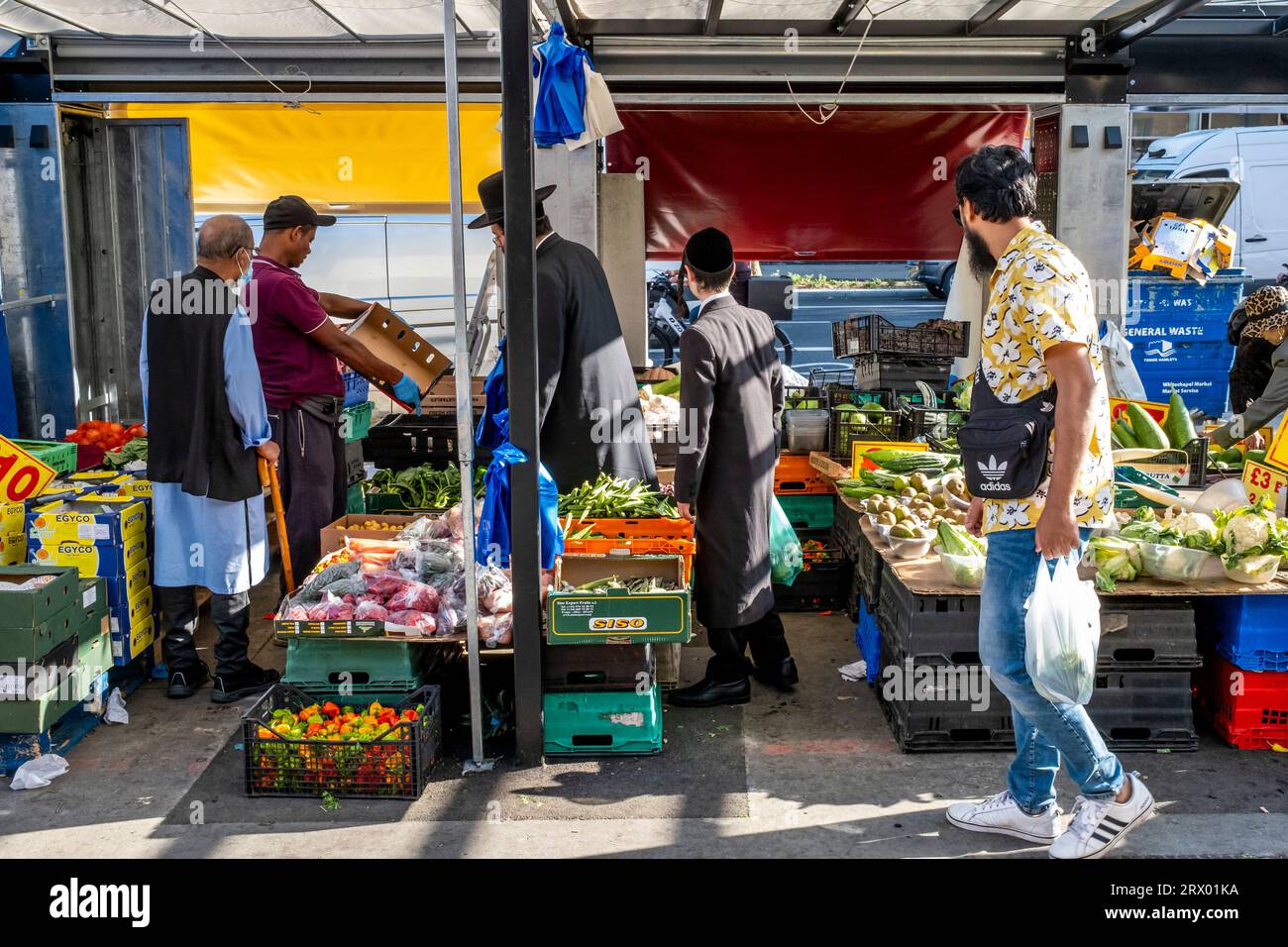 Gli ebrei ortodossi fanno shopping presso Un negozio di frutta e verdura a Whitechapel Road, Londra, Regno Unito. Foto Stock