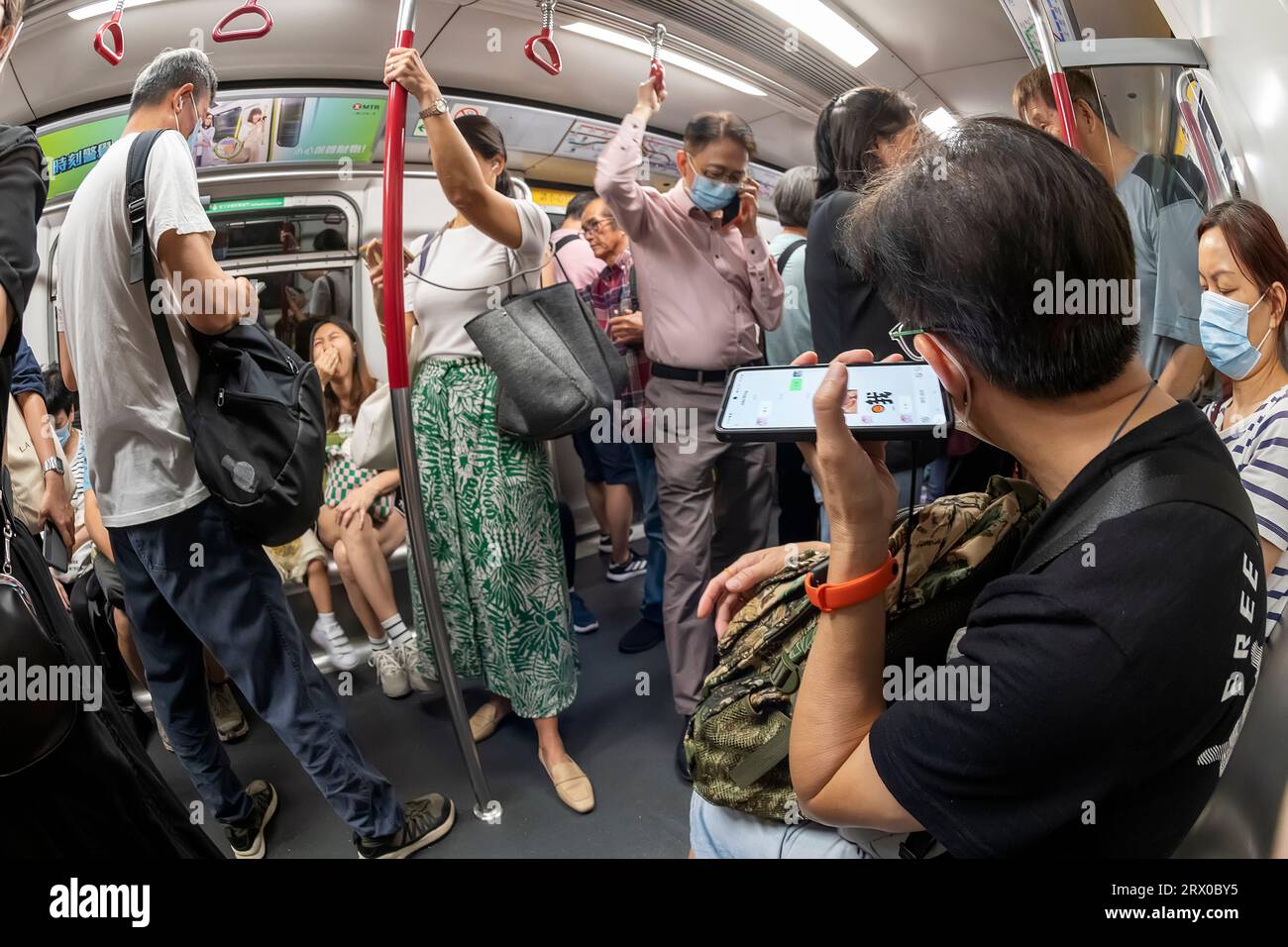 I passeggeri che utilizzano i telefoni cellulari su Hong Kong metropolitana MTR, Hong Kong, Cina. Foto Stock