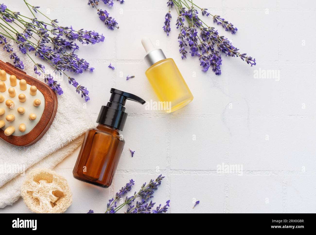 Vasca idromassaggio con lavanda. Sale di lavanda, olio essenziale naturale, spazzole per massaggi e lavanda fresca su fondo di piastrelle bianche. Foto Stock