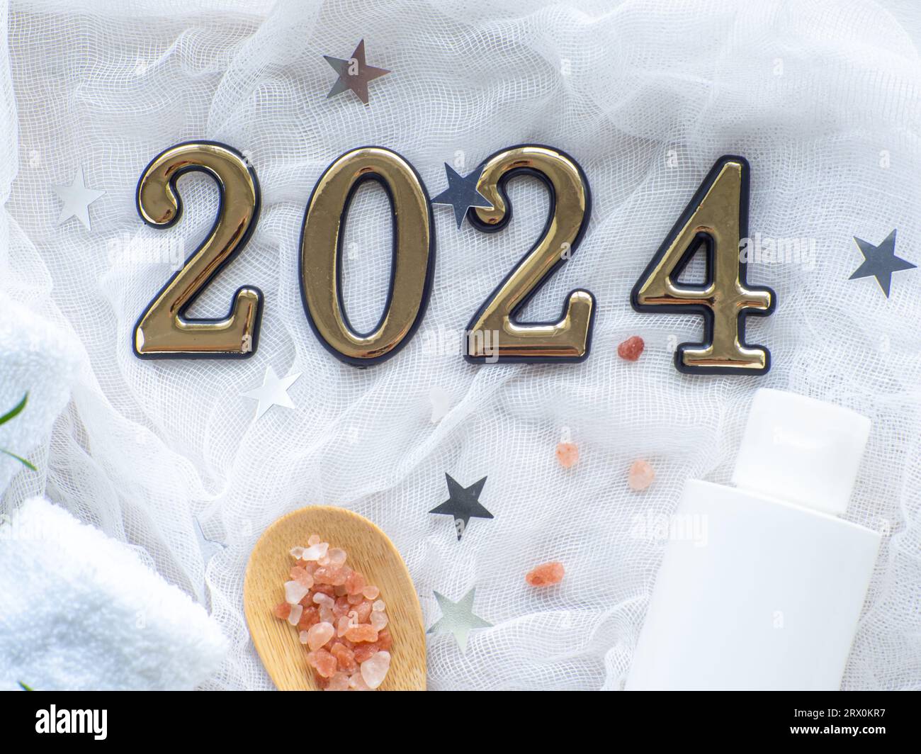 Composizione natalizia con 2024, asciugamani, sale marino e prodotto per la cura del corpo in bottiglia. Tessera benessere Capodanno. Natale, corpo e cura della pelle. Hygie Foto Stock