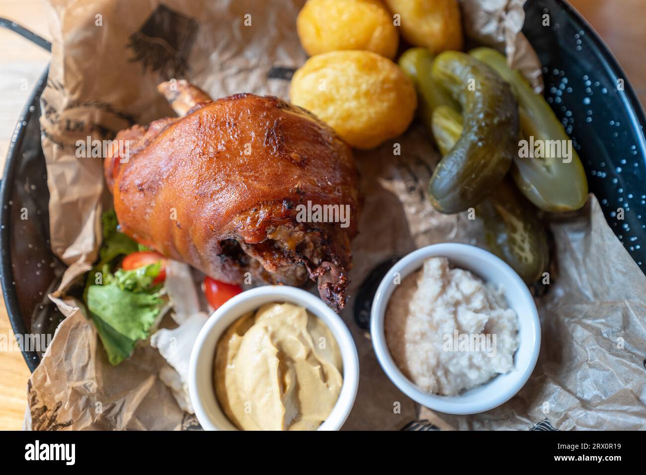 Gambo di maiale al forno servito con patate al forno, rafano, senape e cetrioli sottaceto. Piatto tradizionale polacco Foto Stock