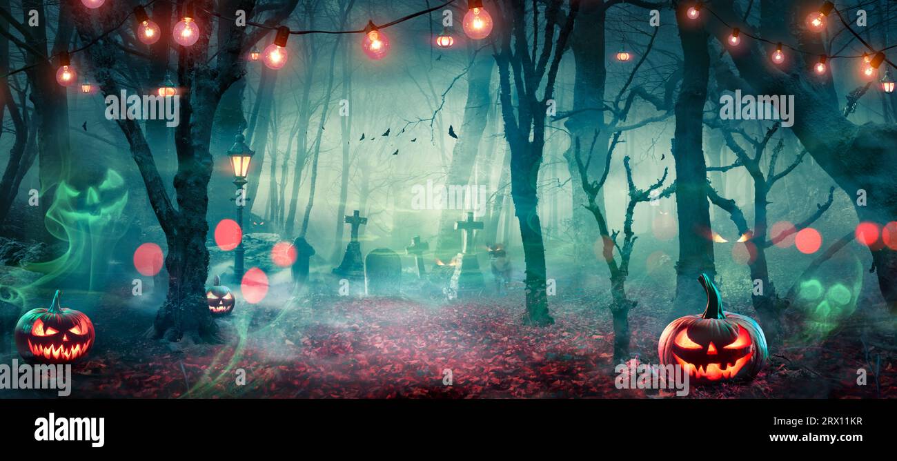 Halloween - Hunted Forest with Pumpkins and Ghosts at Moonlight - Jack o' Lanterns in Cemetery with String Light at Twilight Foto Stock
